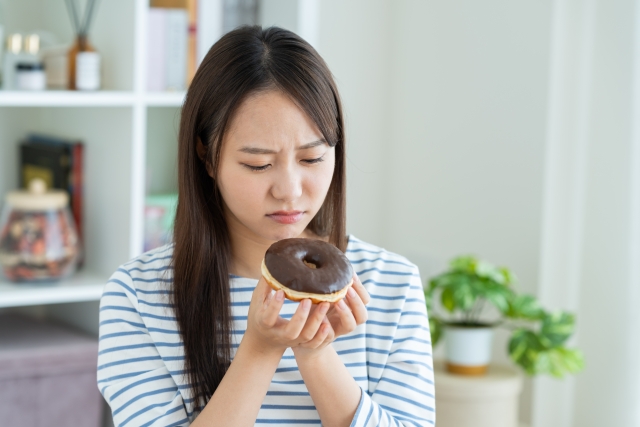 砂糖入りお菓子を我慢する女性
