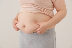 姿勢が悪いのでお腹がぽっこりでている女性