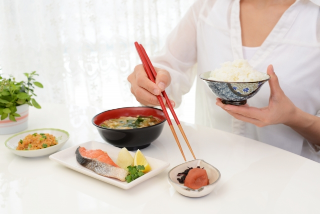 食事の時間を気にして食べる女性